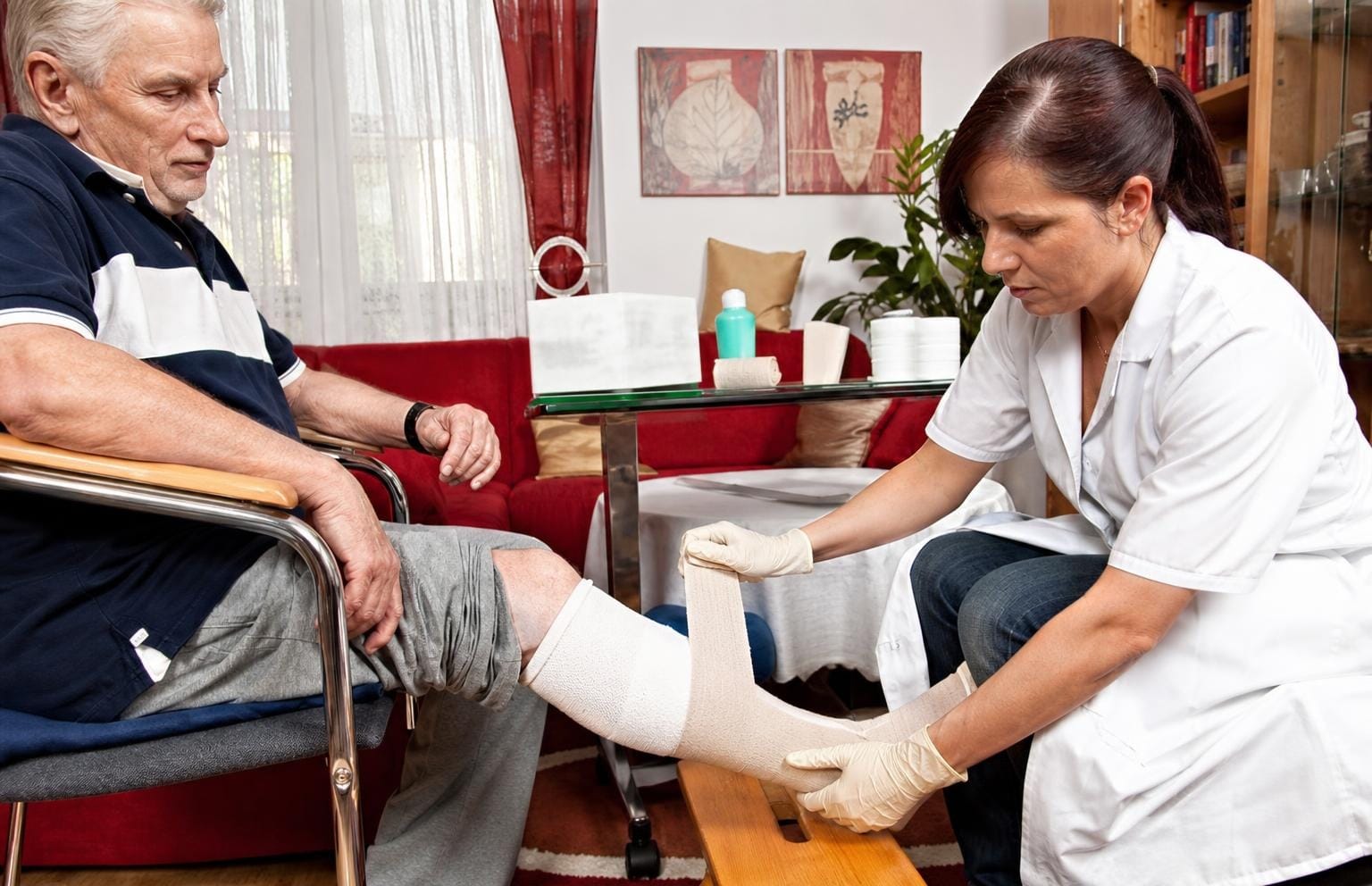 Pflegekraft hilft einer älteren Frau beim Anziehen der Schuhe in ihrer Wohnung